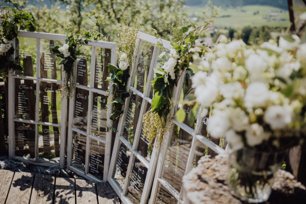 Mit weißen Blumen dekorierter Sitzplan vor der grünen Landschaft des Mondseelands
